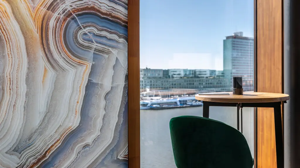 Vescom Bely digital print wallcovering with an agate design and linen texture in a hospitality interior with a river view.