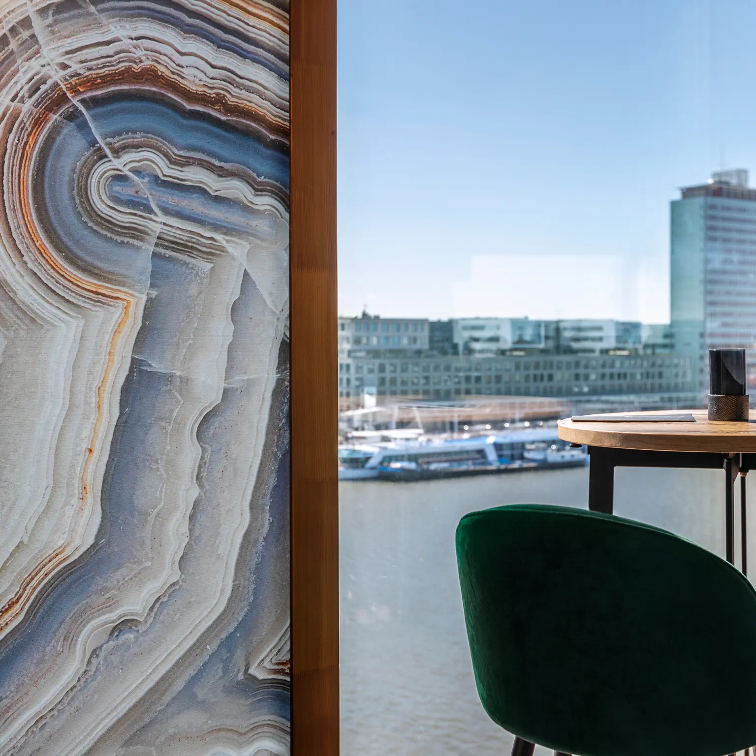 Vescom Bely digital print wallcovering with an agate design and linen texture in a hospitality interior with a river view.
