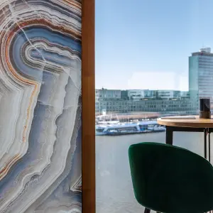 Vescom Bely digital print wallcovering with an agate design and linen texture in a hospitality interior with a river view.