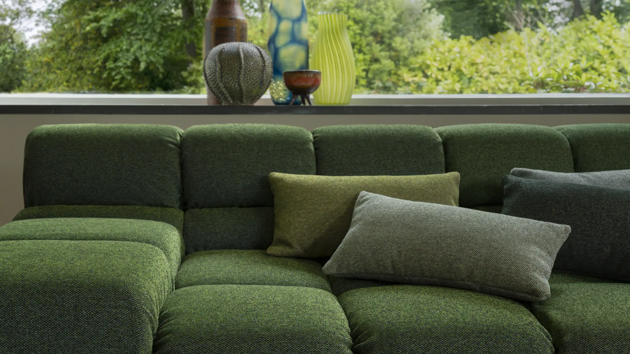 Green seating in Vescom Bosco upholstery nestled among lush foliage.