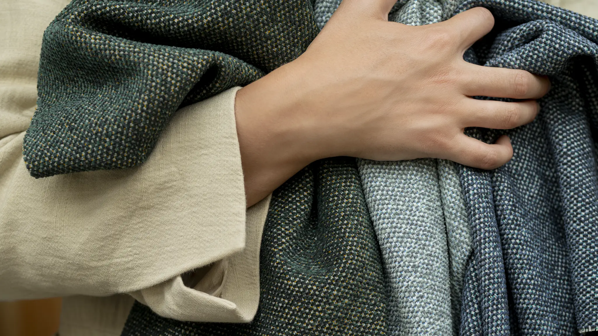 A hand folds green Vescom Bosco upholstery to show its fluid, flexible quality.