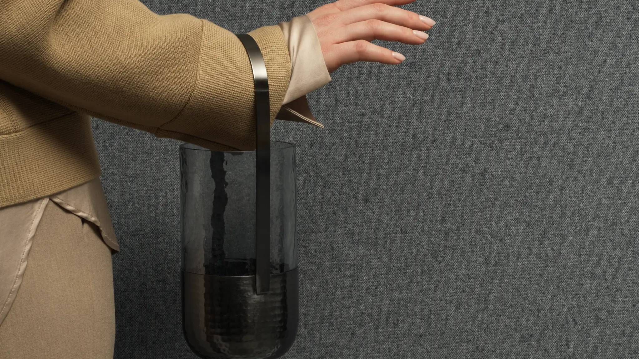 escom Amare textile wallcovering with a dense woollen melange texture creating a warm enveloping surface, shown on interior walls behind a styled figure holding a glass lantern