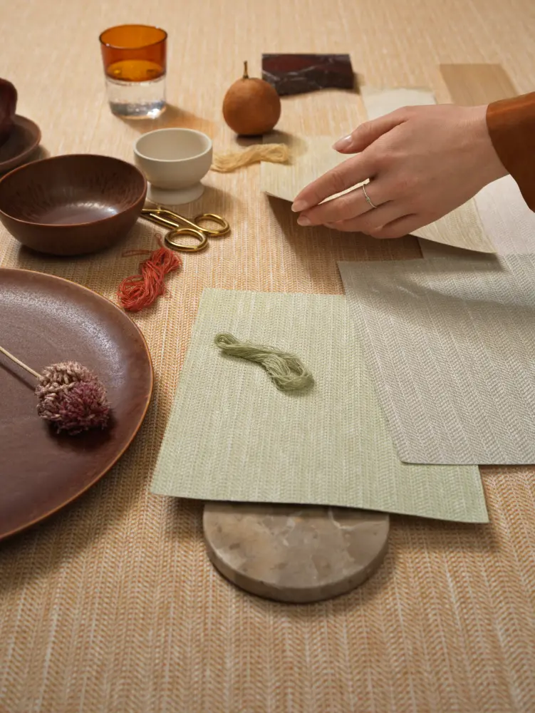 Vescom Sisu textile wallcovering with a structured herringbone weave, creating a measured and rhythmic surface, shown with material samples in a styled interior setting