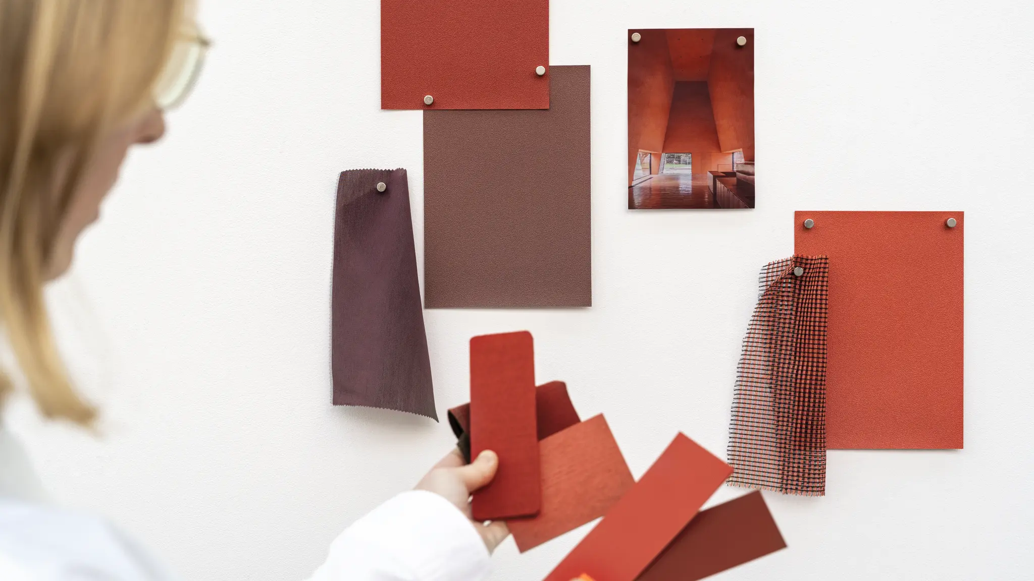 Vescom Colour Choice custom colour development, person with red toned wallcovering samples