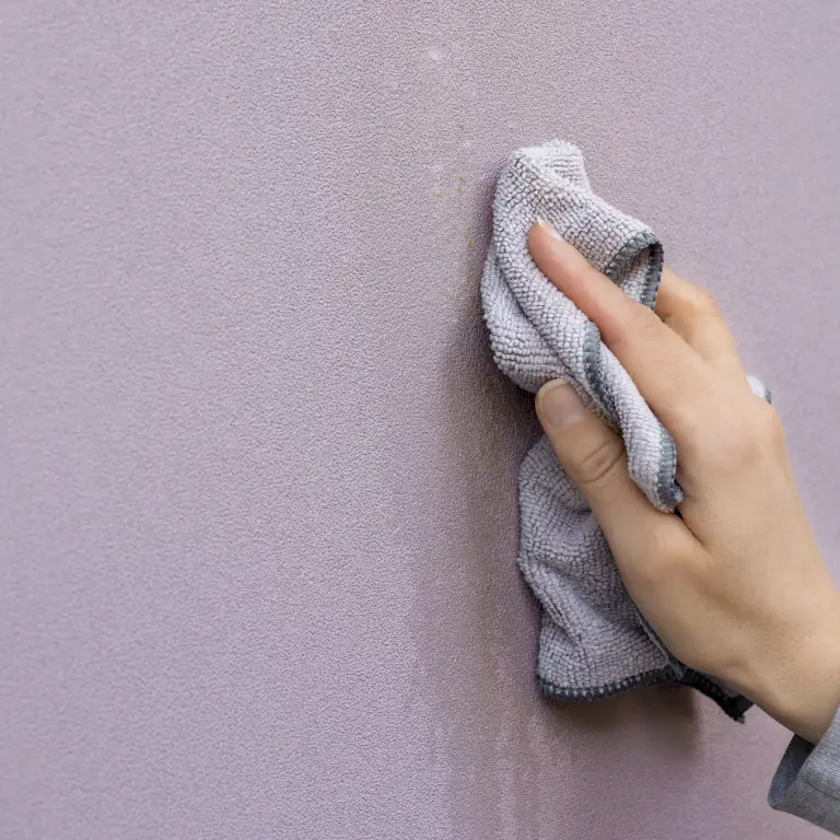 Vescom Colour Choice vinyl wallcovering with a hand removing marks using a cloth