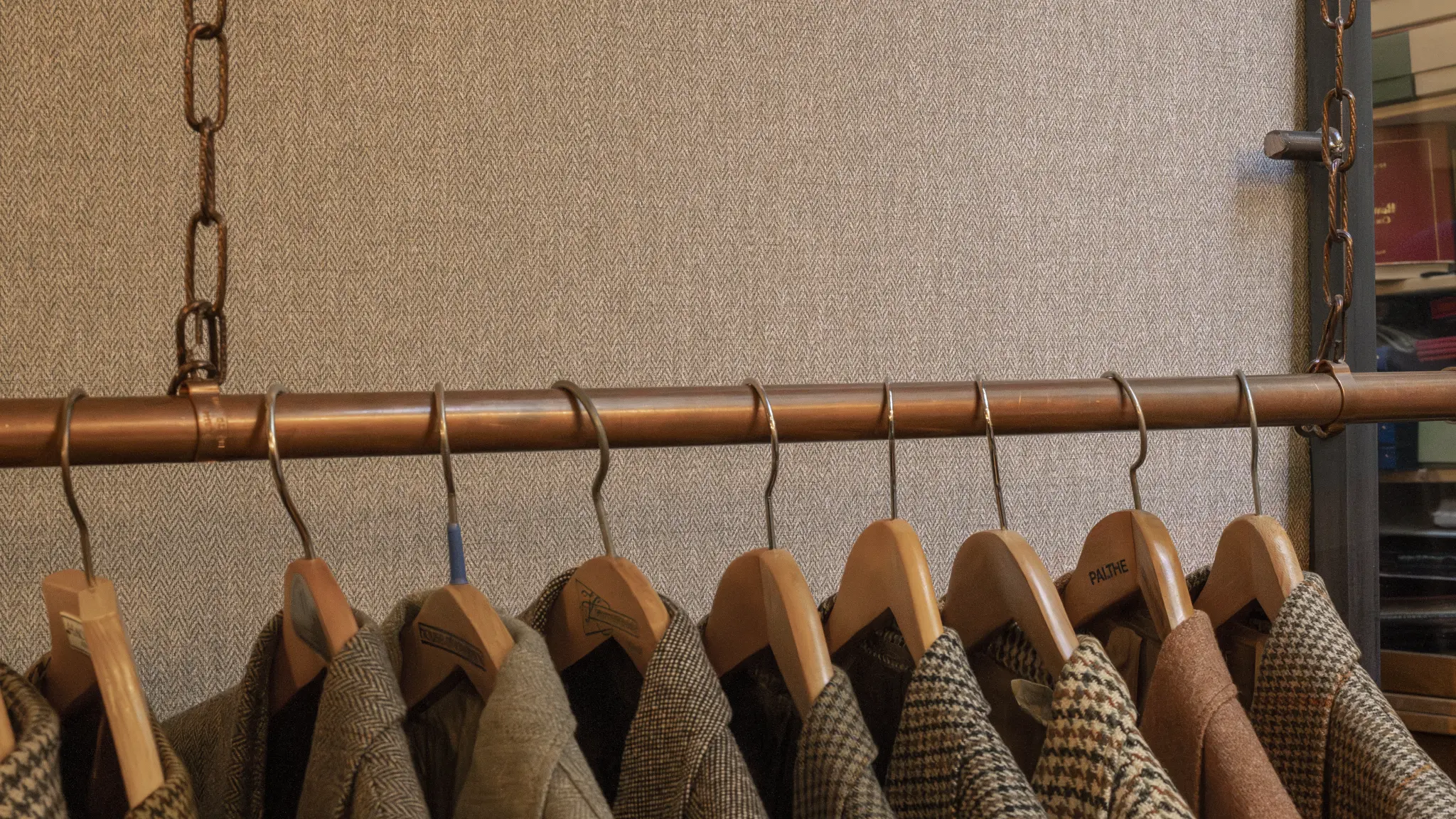 Tailoring-inspired display with fabric samples and warm herringbone textures for Vescom Harrison wallcovering.